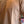 A close-up of a person wearing a short-sleeve crewneck t-shirt in a warm tan or light brown color.