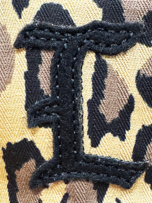 Close-up of a leopard-print fabric patch with a large black embroidered letter 'I'.